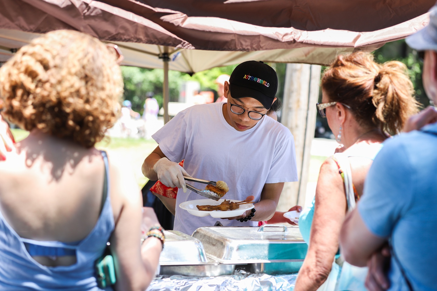 A Royal East Restaurant employee serves festival attendees Asian cuisine offerings from the restaurant's menu.
