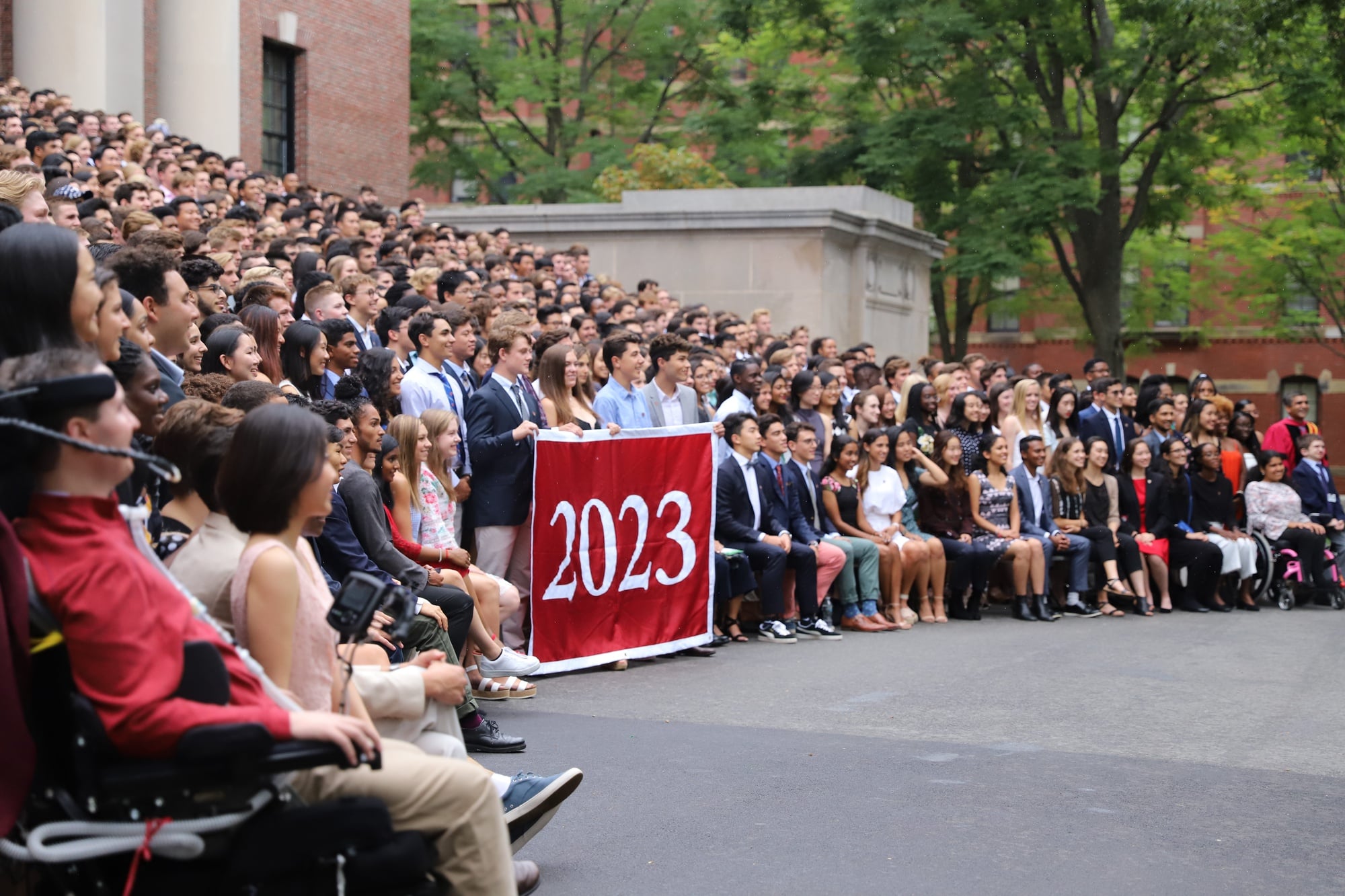 The Class of 2023 gathers to take a class photo on Widener steps despite the rain.