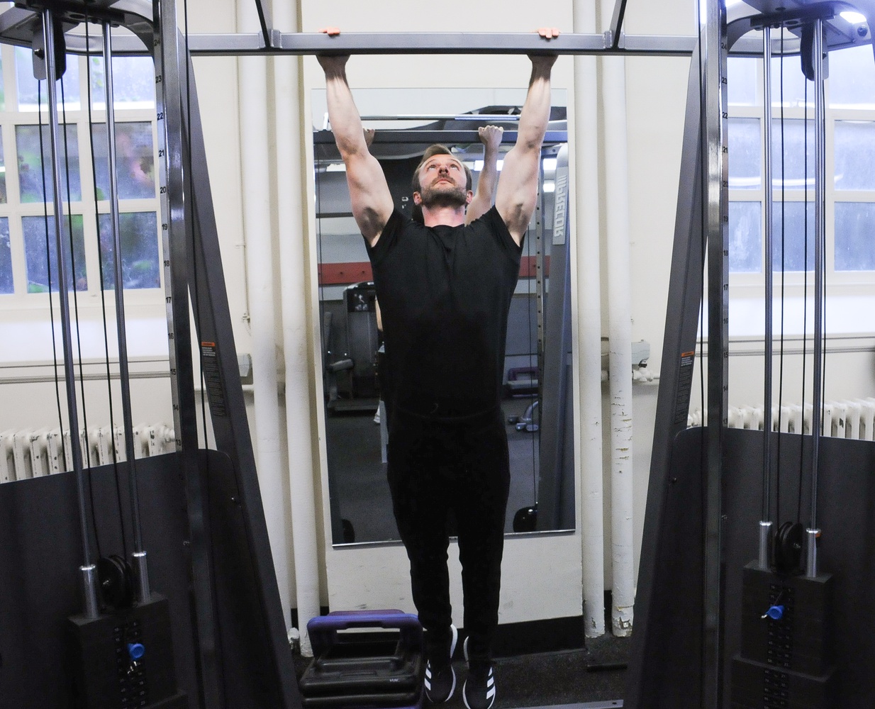 Harvard lecturer Adam E. A. Sandel ’08 does pull-ups in the Malkin Athletic Center.