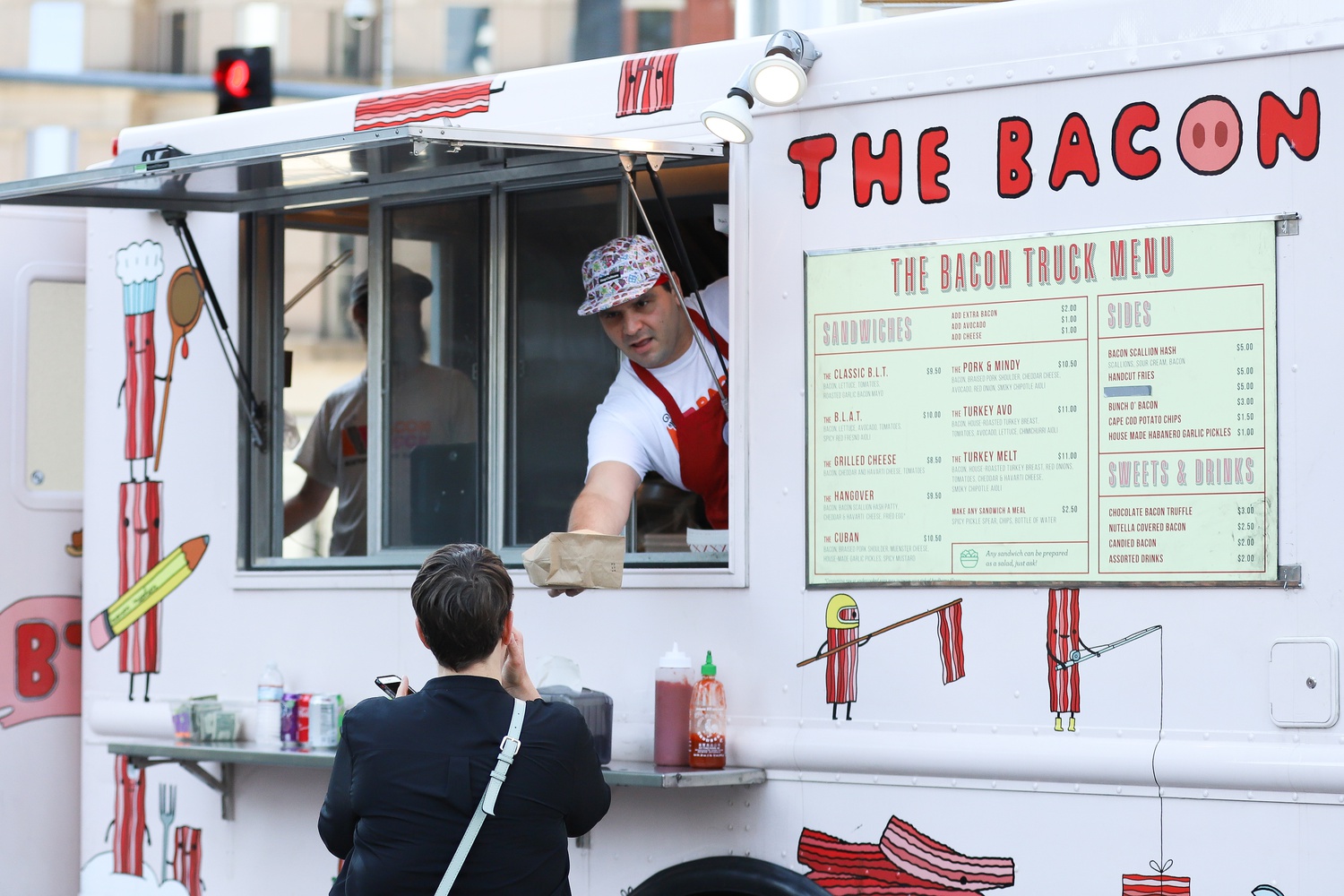 A Bacon Truck employee hands a customer their order at the truck's Dewey Square location Sunday afternoon.