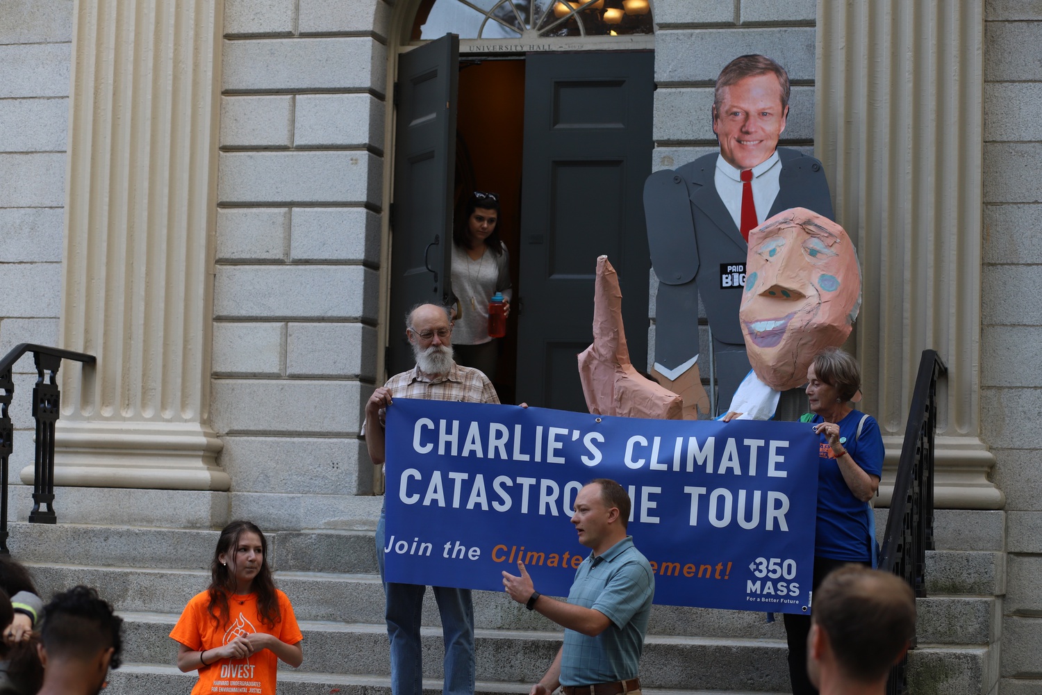 Members of Divest Harvard and 350 Mass for a Better Future joined together on the steps of University Hall to host a mock press conference with figureheads of University President Lawrence S. Bacow and Mass. Governor Charlie Baker.