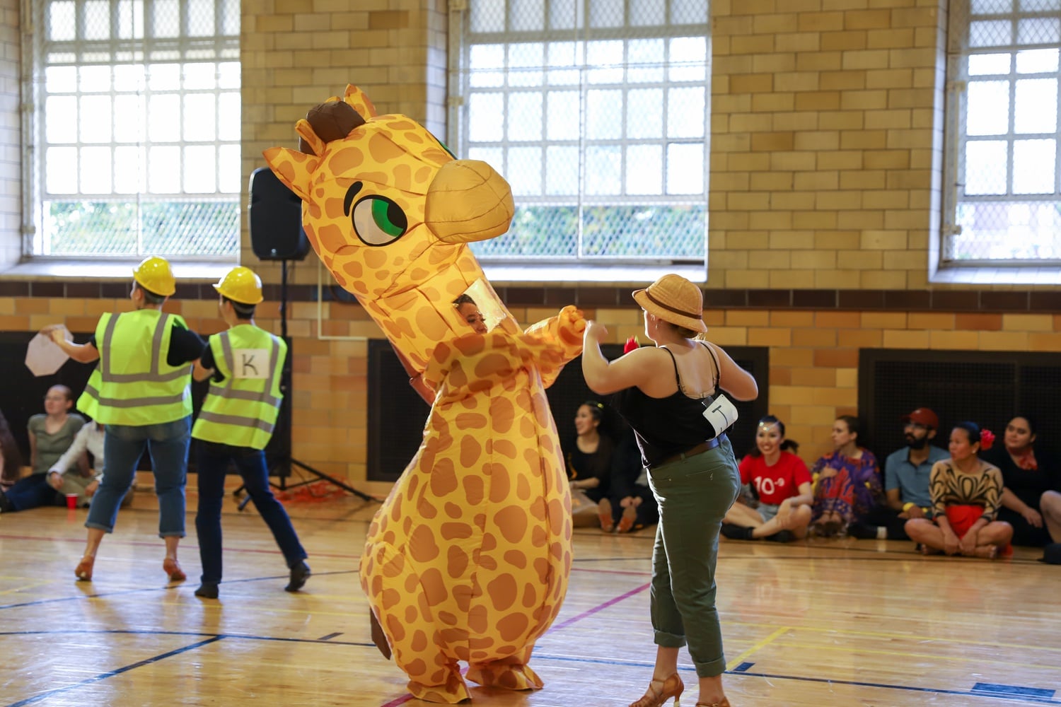Several dancers at the Harvard Beginners ballroom competition dressed in zany costumes, including inflatable dinosaur and giraffe costumes.