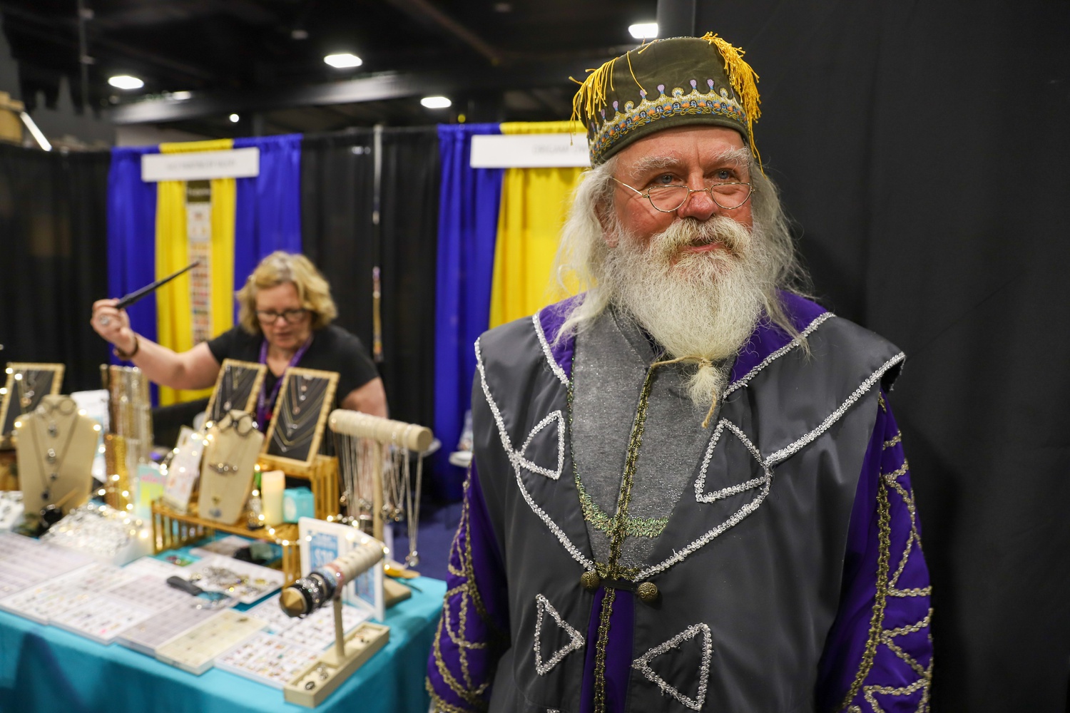 Dave P. Maccawley, cosplaying as Albus Dumbledore, attends his first LeakyCon with his wife Laura, selling jewelry and small trinkets.