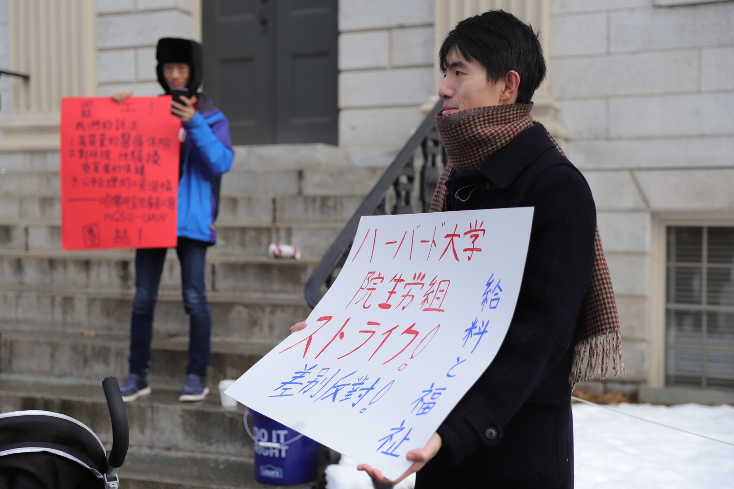 A protester on the Harvard Graduate Students Union-United Automobile Workers picket line holds a sign supporting the strike and key contract measures.
