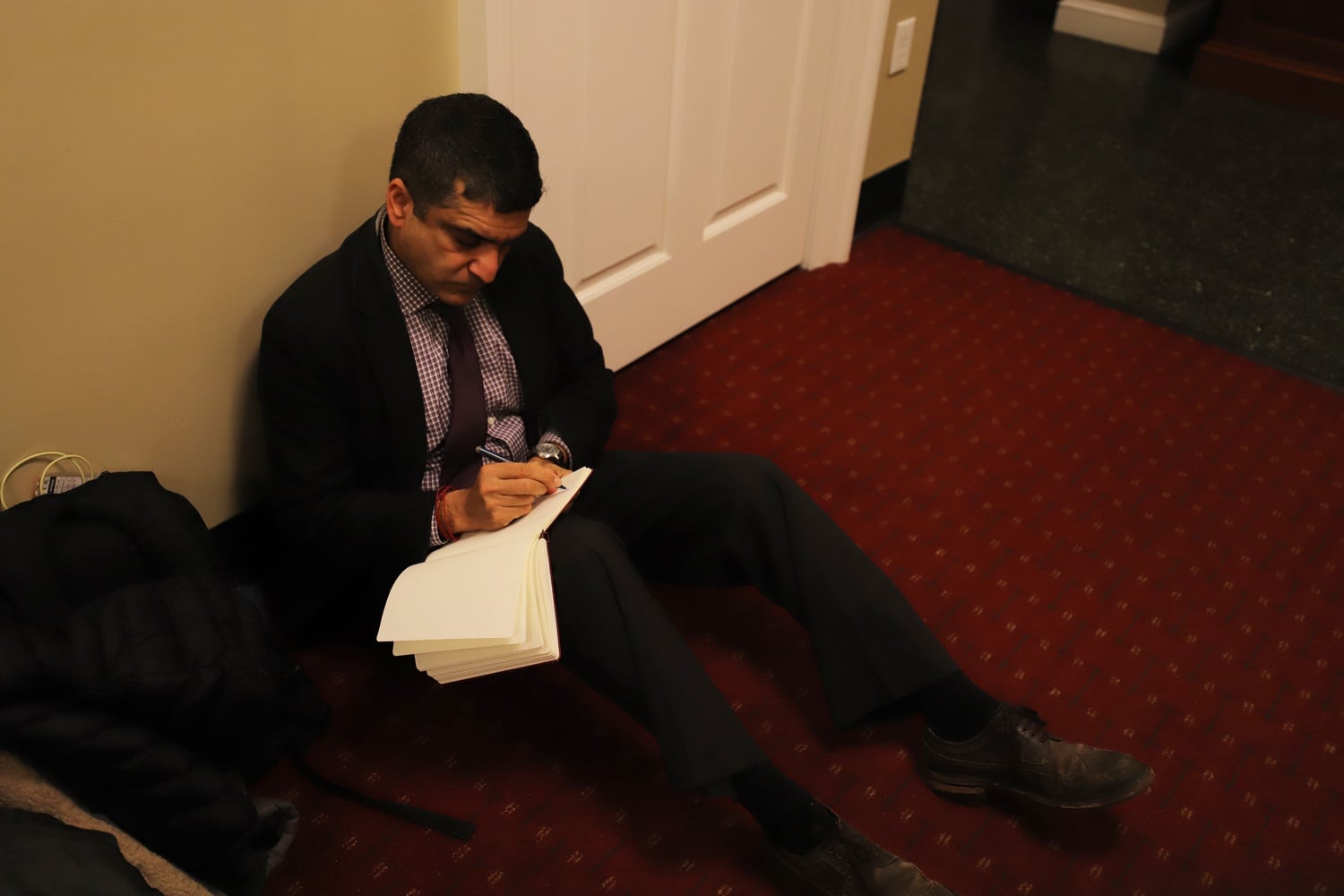 Dean of the College Rakesh Khurana takes notes while watching students occupy the Harvard Office of Admissions and Financial Aid.