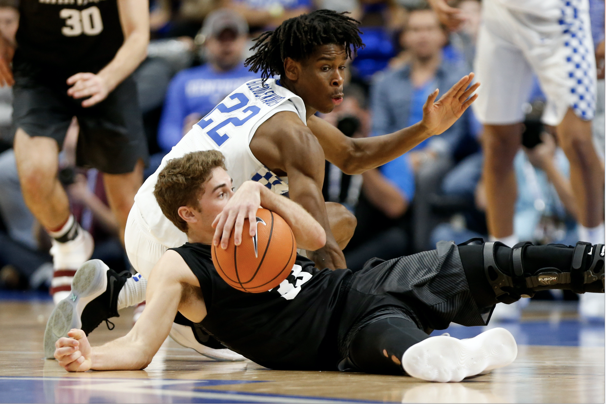 Farley diving to the ground in front of Kentucky's Shai Gilgeous-Alexander, now a member of the Oklahoma City Thunder averaging nearly 20 points per game.