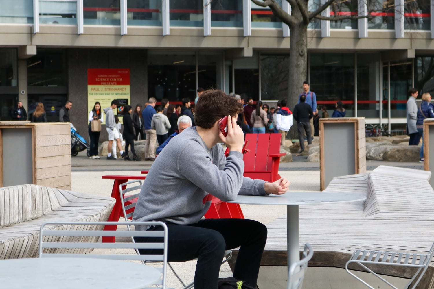A Harvard undergraduate talks on the phone in the Science Center Plaza, reacting to the University's decision to send undergraduates home due to the coronavirus outbreak.