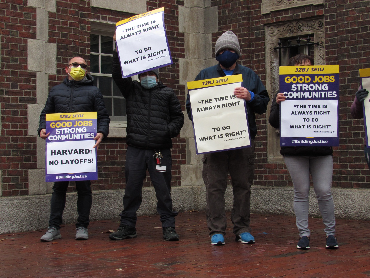 Itamar San Giorgio, left, a contracted custodian who works at Widener Library, protests Harvard's impending layoffs with fellow 32BJ SEIU members next to the Widener Gate.