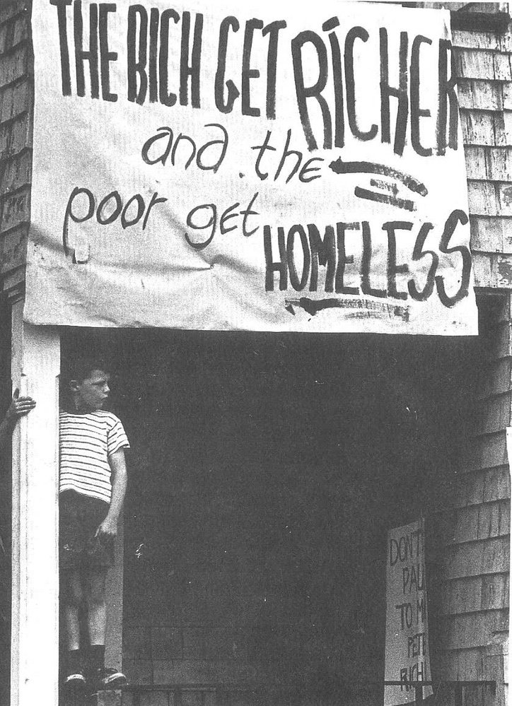A sign on a building in Barry's Corner in Lower Allston in the 1960s. It reads, “The Rich Get Richer and the Poor Get Homeless.”