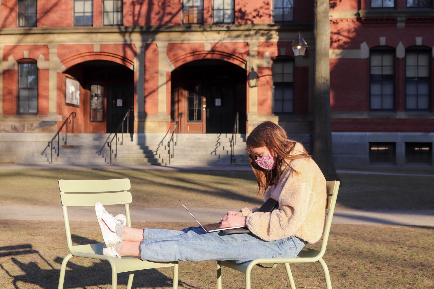 Layla Seaver '24 uses a laptop in Harvard Yard last month. On March 1, the University switched the campus status to Level 4: Lime, relaxing some of the public health restrictions faced by on-campus students.