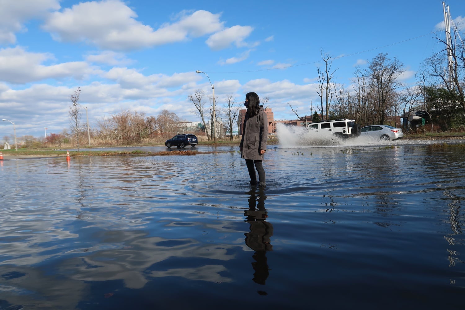 City Councilor Michelle Wu '07 surveys flooding at Morrissey Boulevard in Dorchester. As climate change causes sea level rise, these flooding events will become more common.