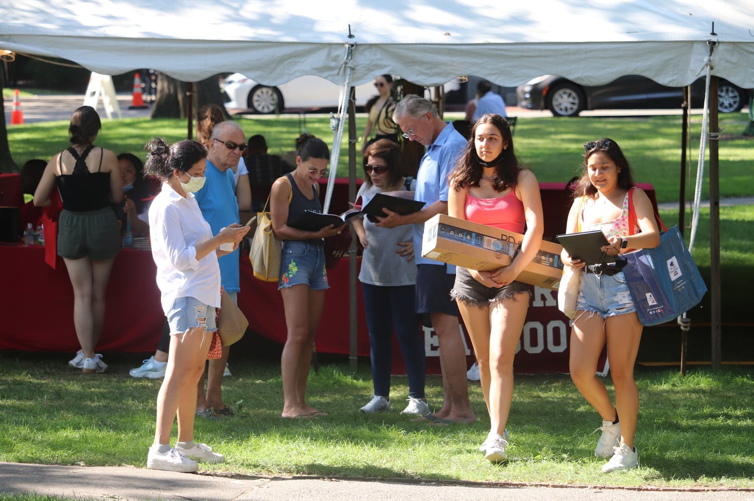 Students walk past the welcome tent set up in the middle of Harvard Yard during freshman move-in.