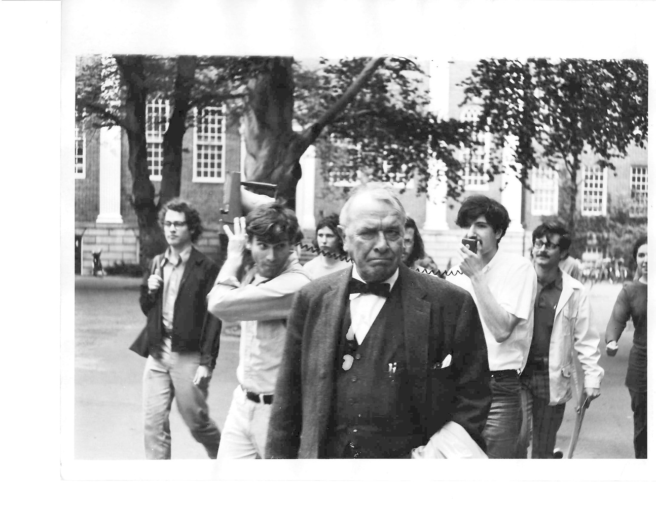 Students for a Democratic Society members tail and shout at Sargeant Kennedy ’28, the Harvard Corporation secretary, through Harvard Yard. Ira D. Helfand ’71 is pictured holding a bullhorn.