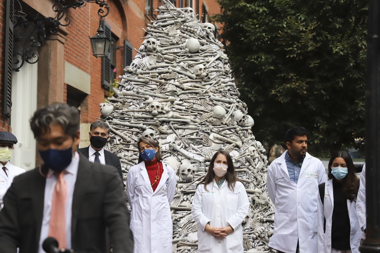 A group of Harvard-affiliated doctors called for global vaccine equity outside the home of Moderna's CEO Wednesday, speaking in front of a 12-foot high display of artificial bones.
