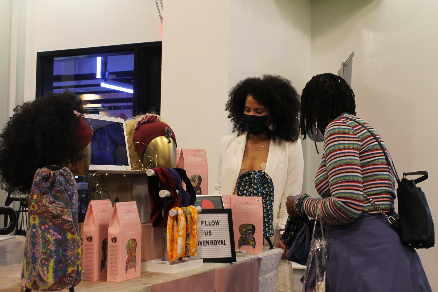 Charlene M. Pena (left) speaks with someone beside the Woven Royal display table at Soulfully Textured. Pena, the founder of the Massachusetts-based company Woven Royal, was one of the vendors at the event.