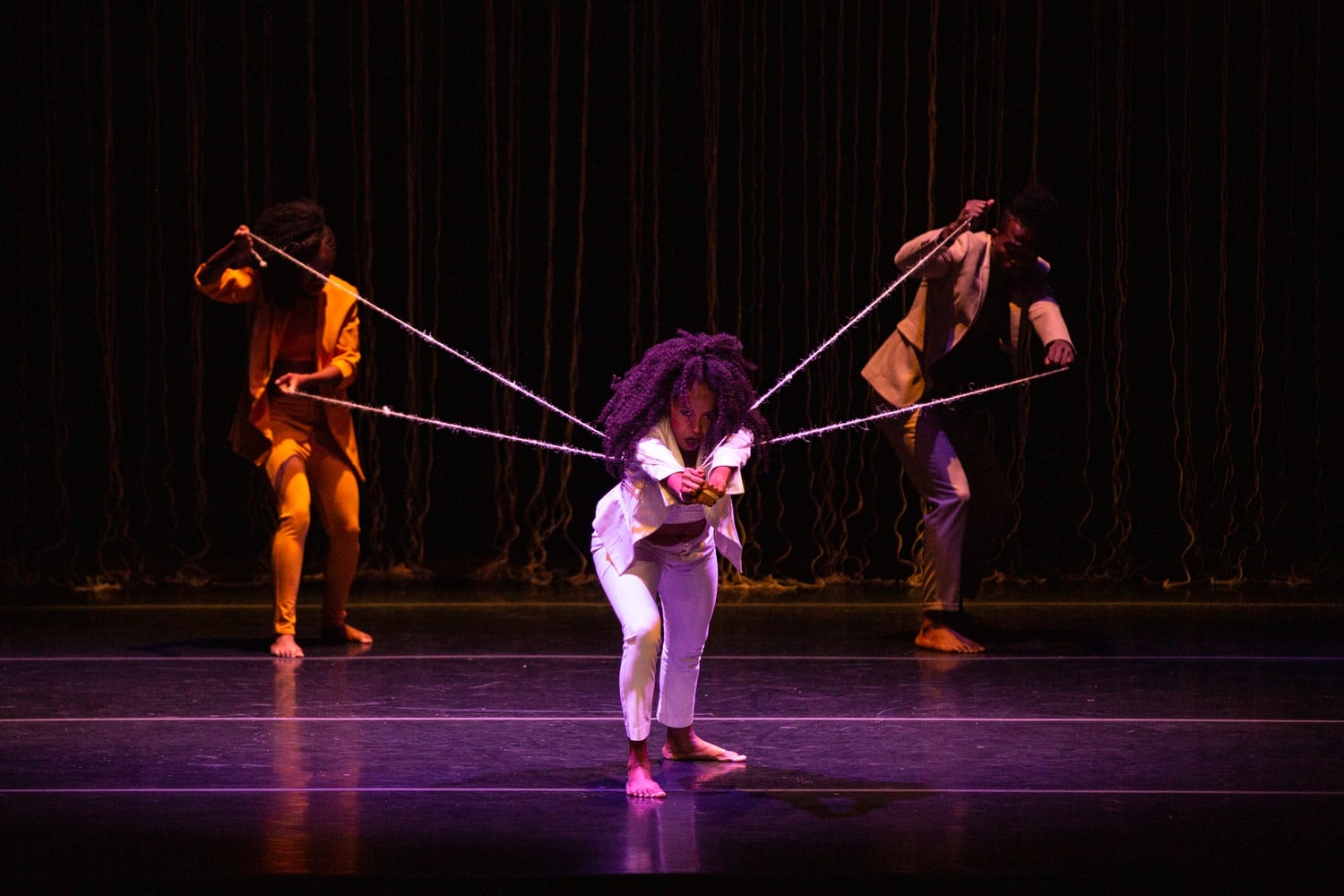 Yndira Perea Cuesta pulls against rope handcuffs held by other dancers during “Accommodating Lie.”