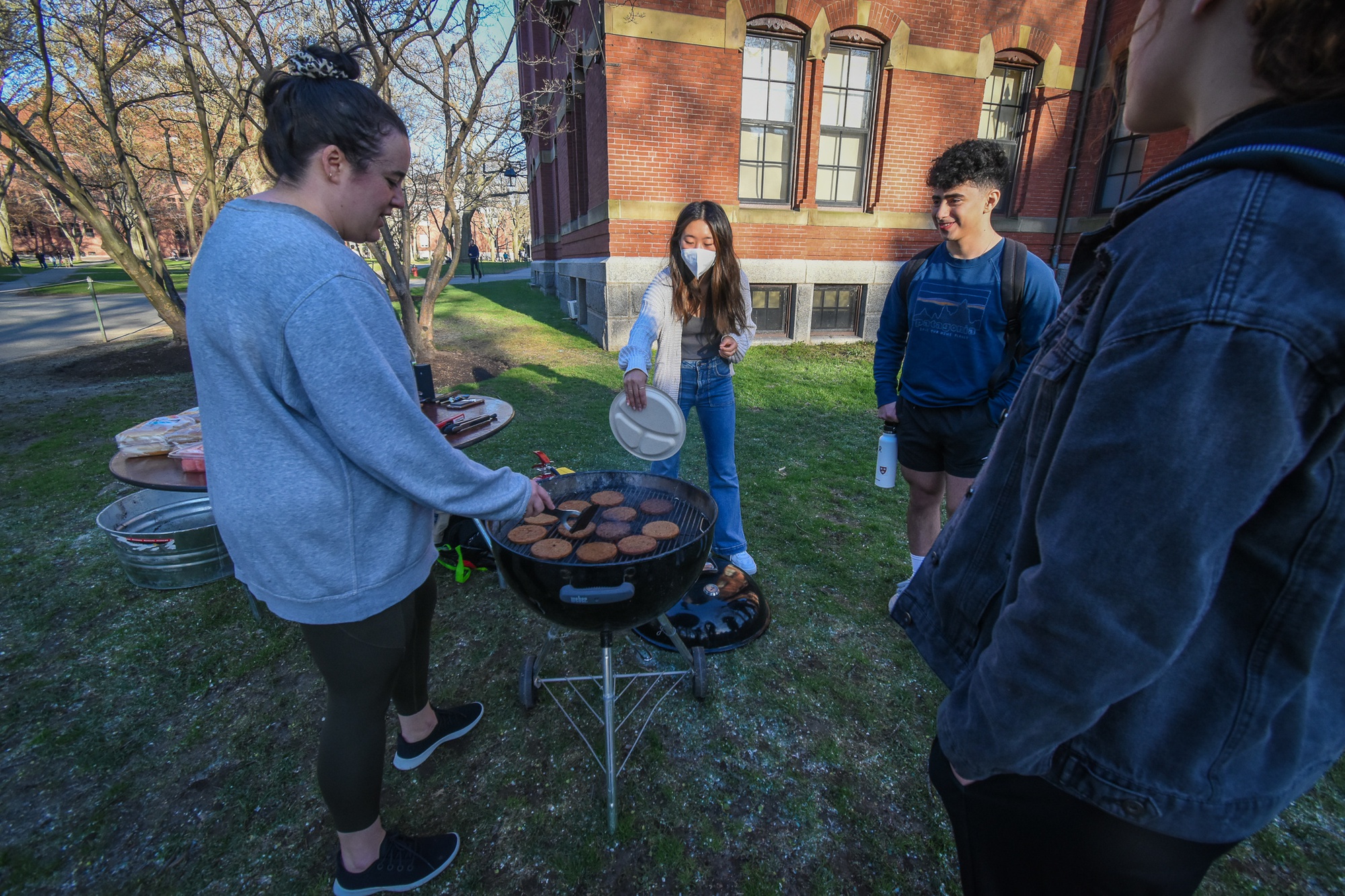 Undergraduates chat and flip burgers at an outdoor cookout near Weld.