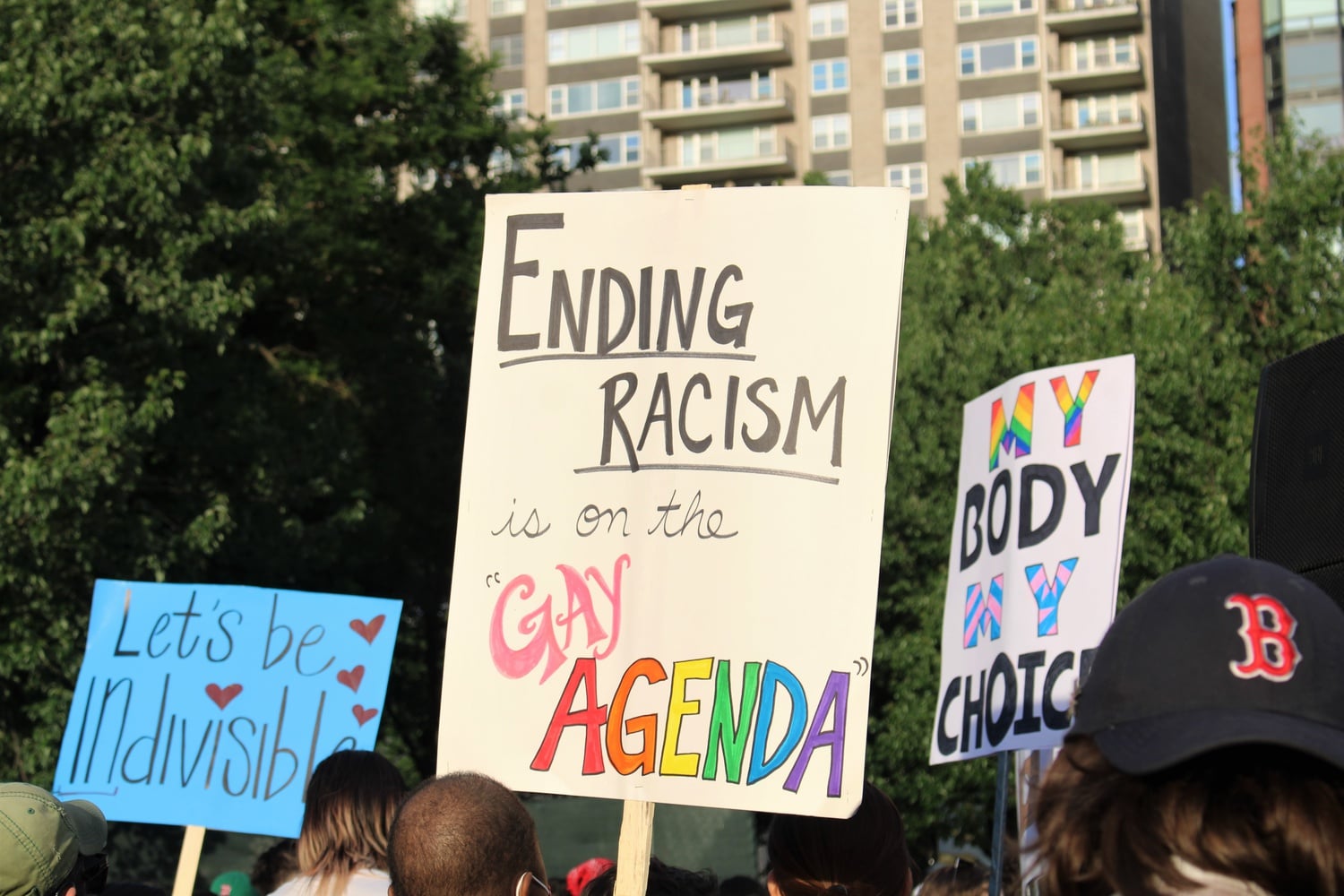 Participants hold up signs reading, "Ending Racism is on the Gay Agenda," and "My Body My Choice" during a Pride celebration in Boston.