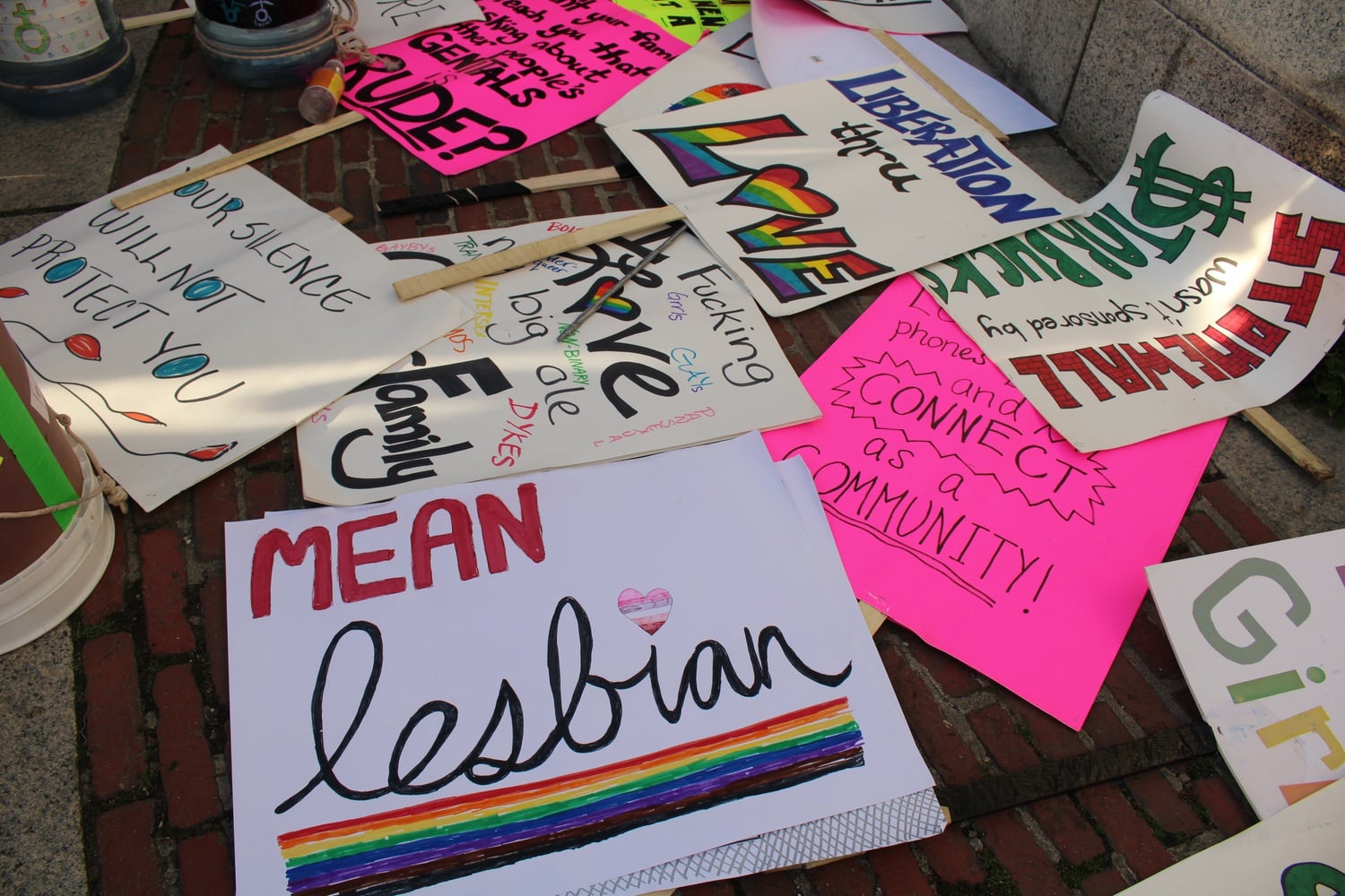 Handmade signs lie on the ground before the start of a Pride celebration in Boston Common.
