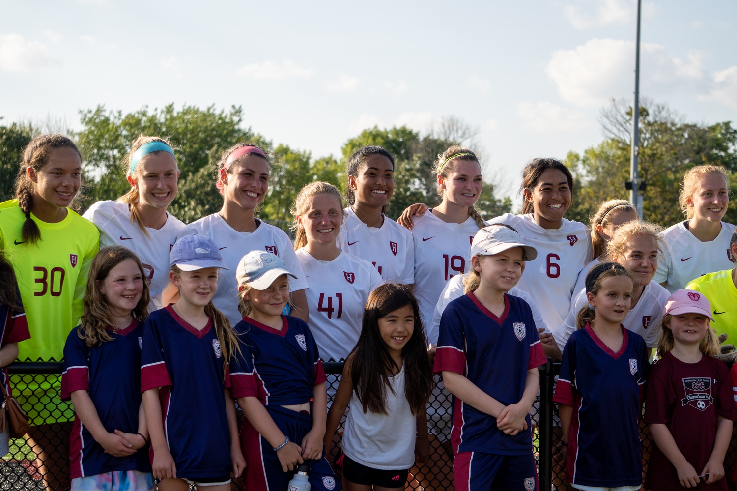 The Crimson poses for a photo after the game with a group of young fans from Belmont Soccer Association who stayed after to ask the team some questions.
