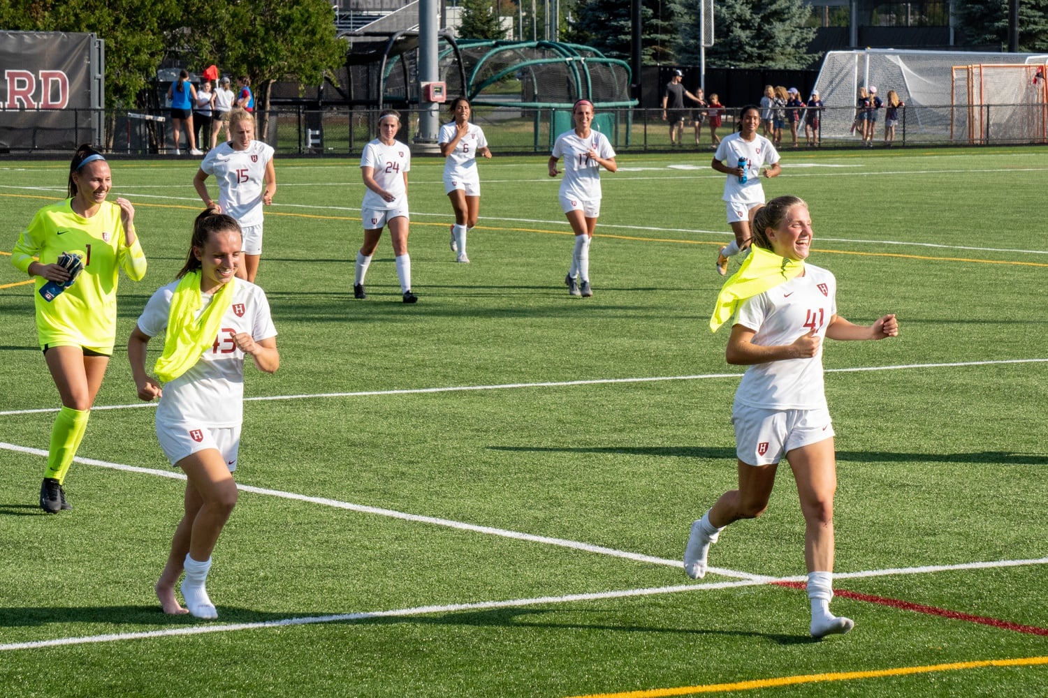 From left to right, junior Anna Karpenko, sophomore Ainsley Ahmadian, and sophomore Hannah Bebar lead the team as they run across Jordan Field to greet fans after Harvard's win over Northeastern on August 29.