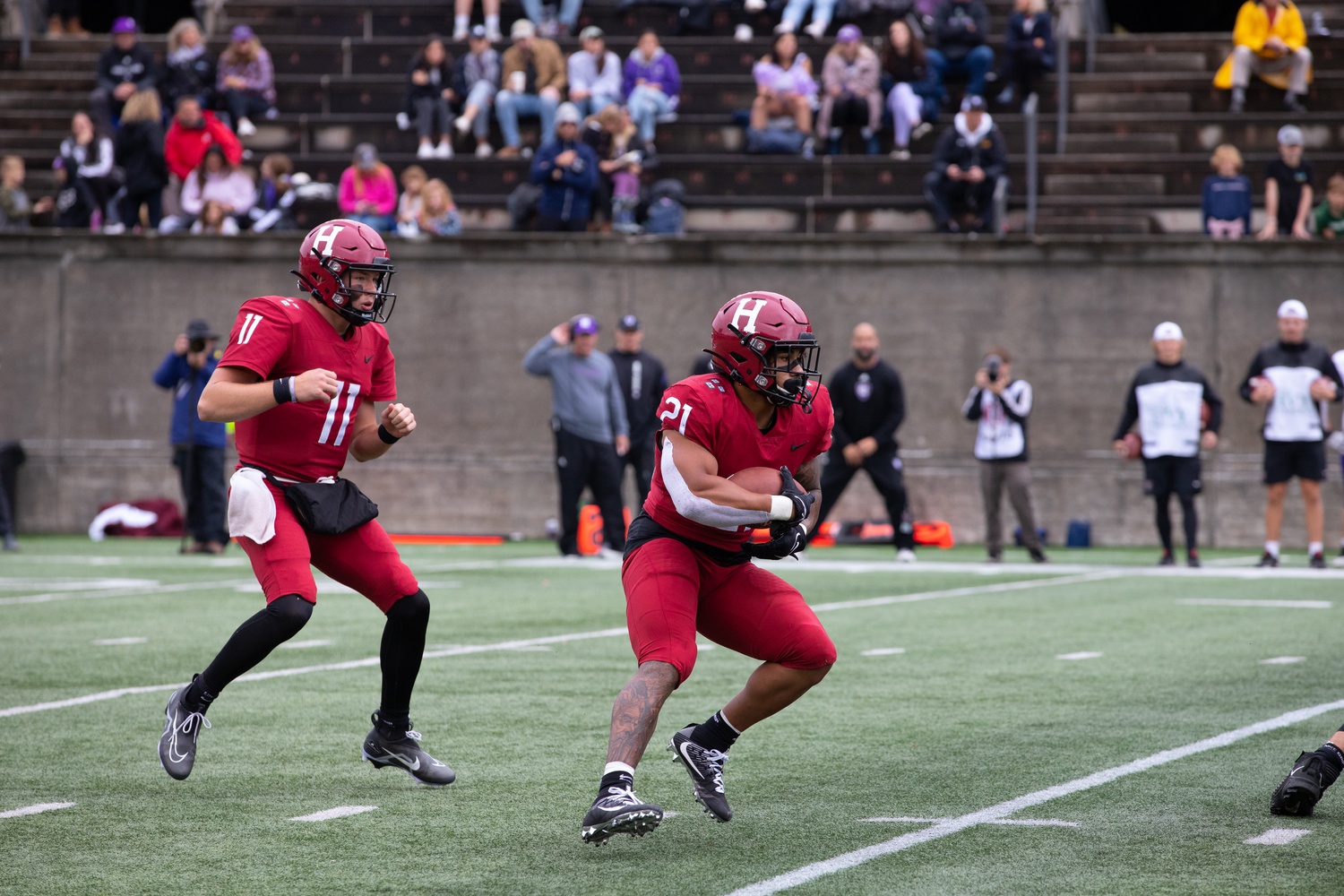 Dean hands the ball off to Borguet in Saturday's 30-21 loss to Holy Cross. Although Harvard lost, both players put up strong performances.
