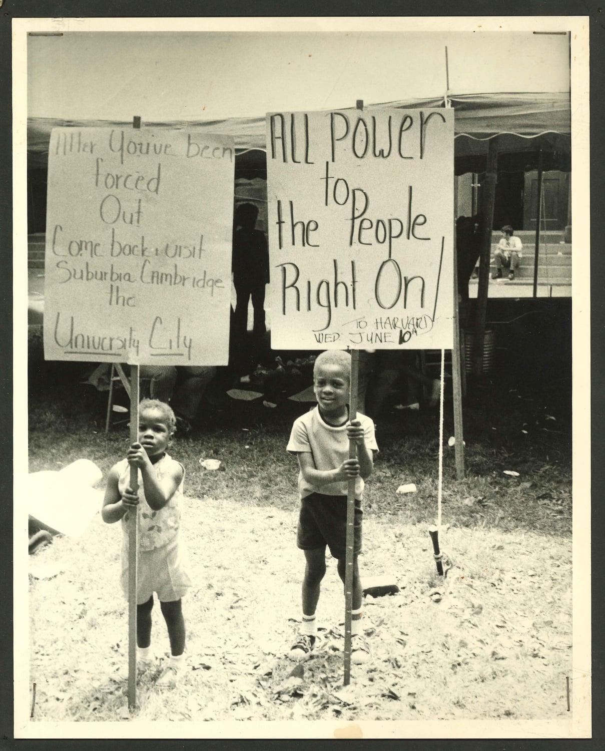 Children hoist signs protesting Harvard's expansion into the Riverside neighborhood.