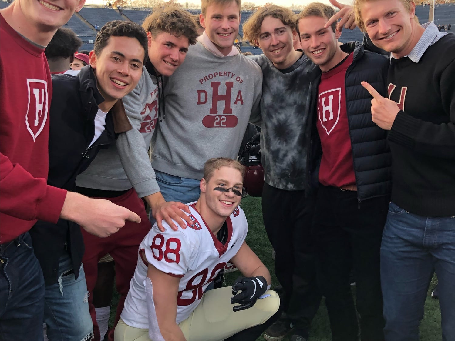 Then-first-year tight end Tyler Neville smiles in a huddle of Harvard students after Harvard-Yale in 2021. Neville made a critical 12-yard reception to open the final drive, playing a key role in ensuring the Crimson's tight victory.