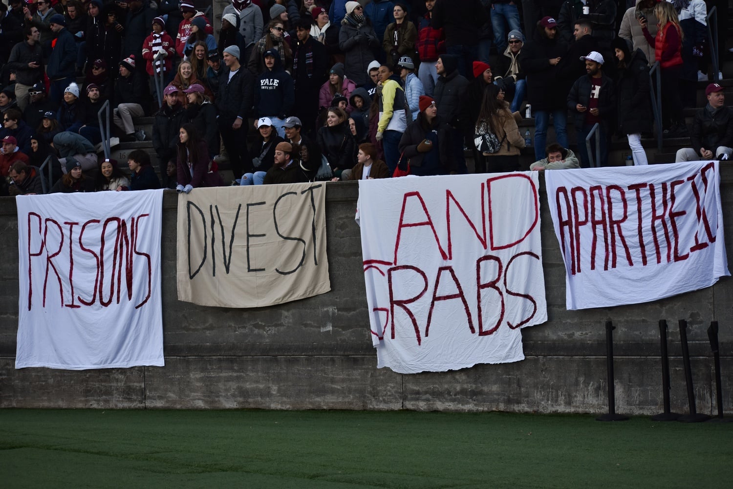 Student protesters held banners over the wall of the stadium during The Game on Saturday.