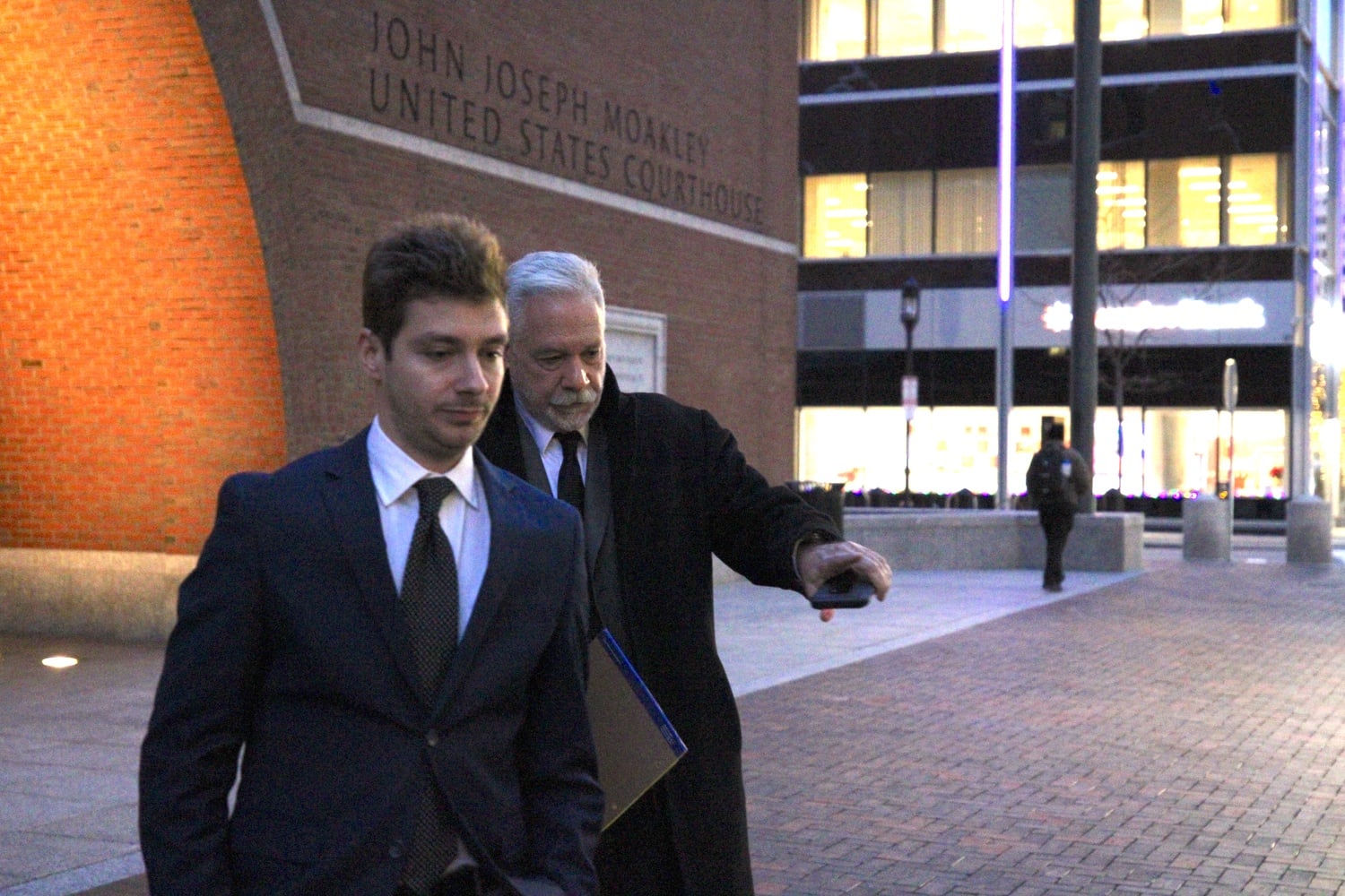 Former Harvard fencing coach Peter Brand, right, exits the John Joseph Moakley United States Courthouse on Monday.