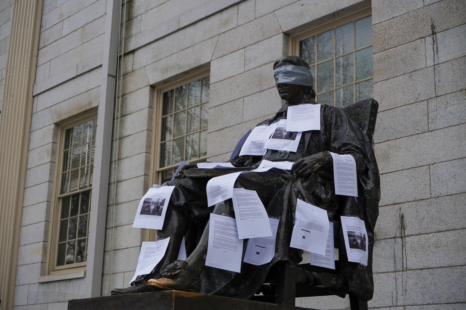 Students plastered articles from The Crimson on the John Harvard statue on Wednesday, highlighting John L. Comaroff’s controversial presence on campus. The display came a day after a student walkout during Comaroff’s first class of the semester.