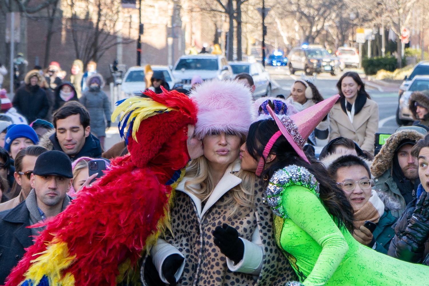 Jennifer Coolidge getting kissed on both cheeks by members of The Hasty Pudding Theatricals.