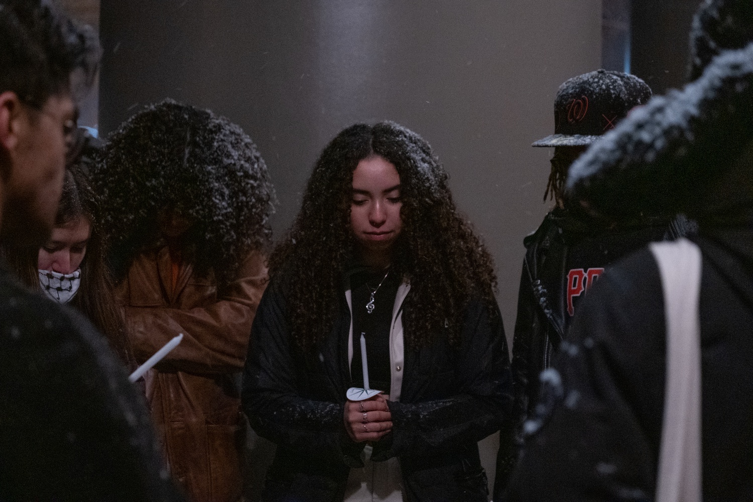 Elyse G. Martin-Smith '25, who performed an original song at the vigil, holds a candle that could not be lit due to the wet and windy conditions.