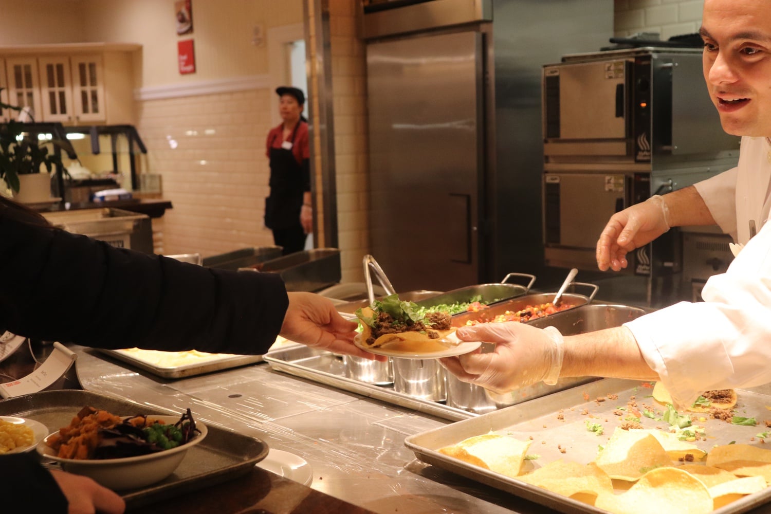 A Harvard University Dining Services employee serves tacos from the Dunster House dining hall grill.