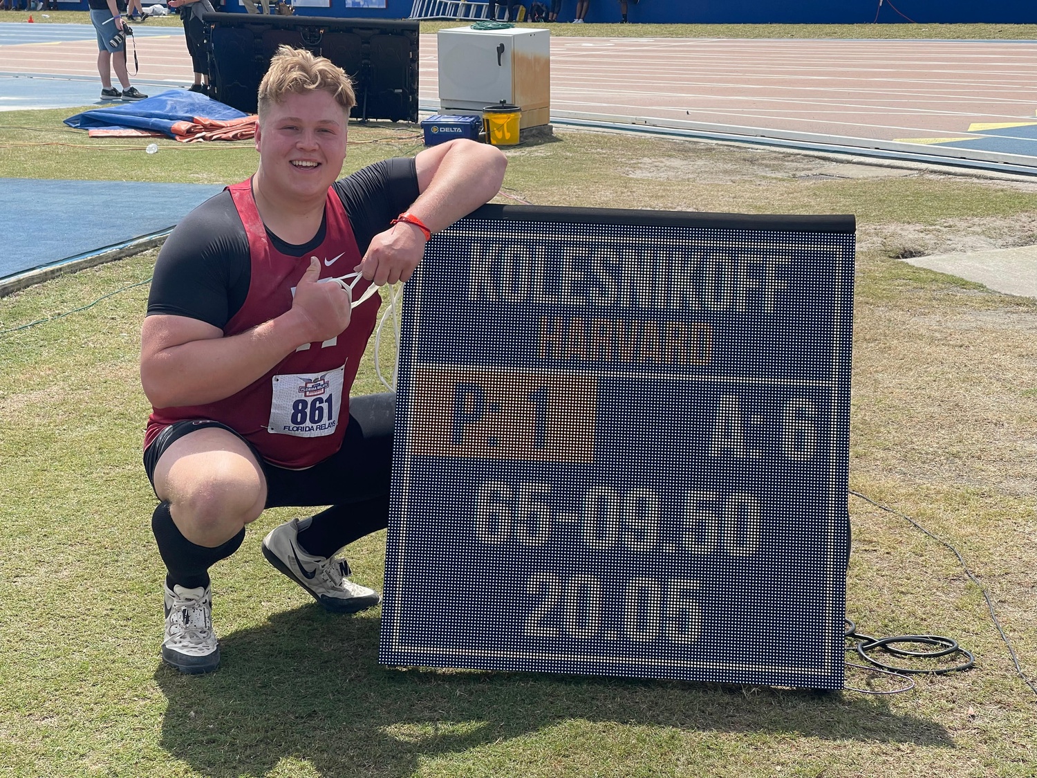 Senior Alexander Kolesnikoff poses next to the scoreboard in Fla., listing his new school record and leading NCAA mark. Kolesnikoff threw a 20.05 m shot put, making him the first in Harvard history.