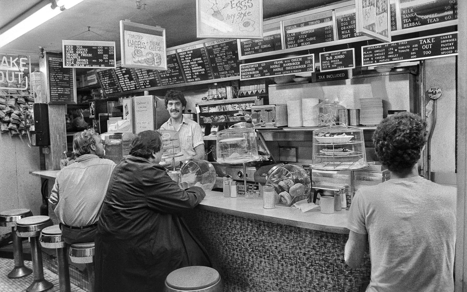The Tasty Sandwich Shop, a diner restaurant in Cambridge, open from 1916 to 1997 at 6 John F. Kennedy St. Behind the counter is chef Don Valcovic, on the right is Al Nidle, publisher of Street Magazine in the late 1980s. The restaurant’s customers ranged from long-time residents to students from Harvard University to bankers and businessmen, all mixing informally. Originally published on page 247 in "Dirty Old Boston," 2014.