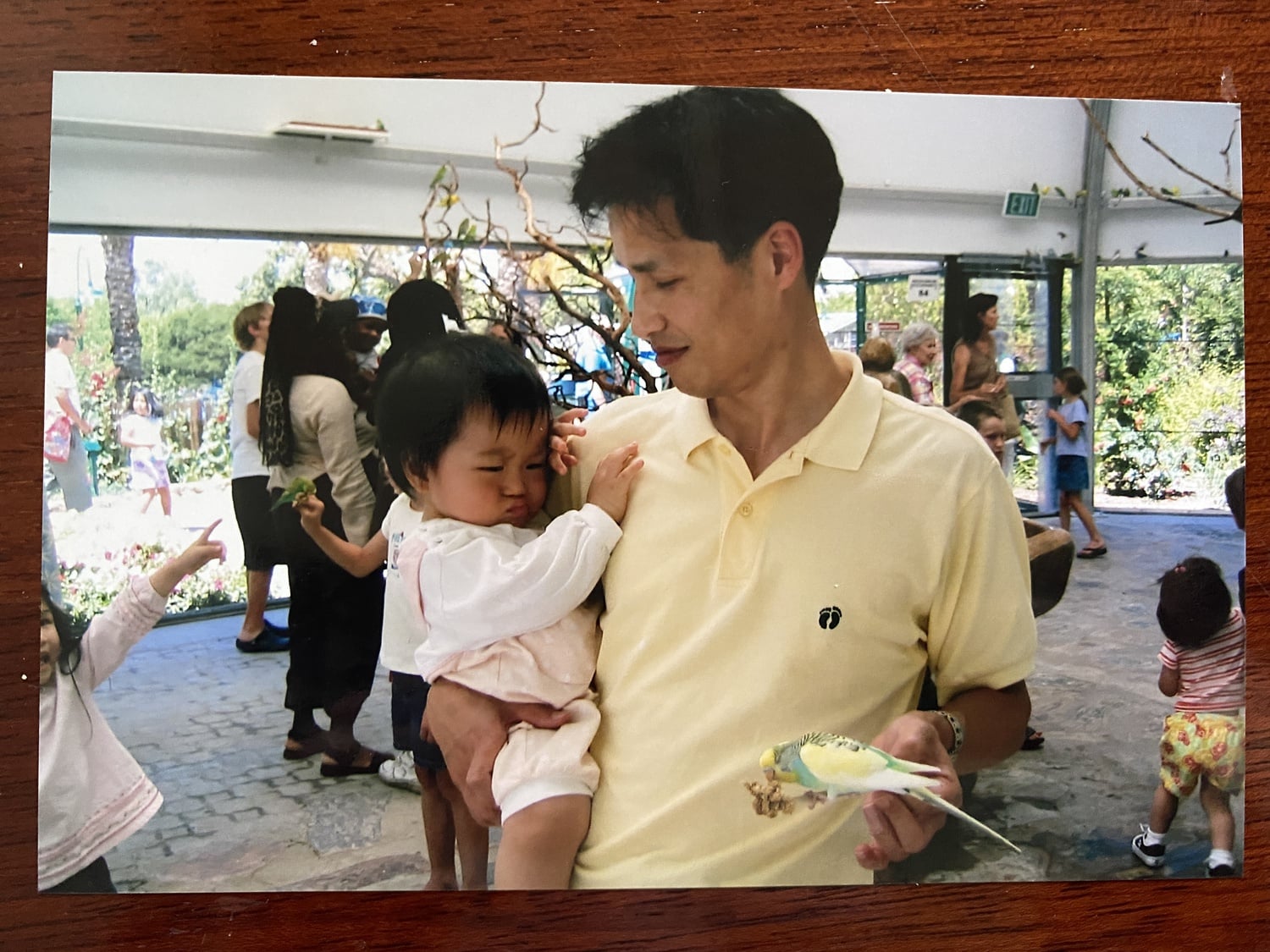The author as a baby in her father's arms, pouting at a bird at a zoo.
