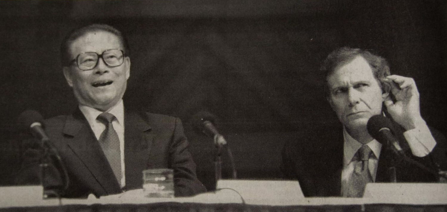 Harvard President Neil L. Rudenstine cranes to listen to an audience member as Chinese President Jiang Zemin answers a question.