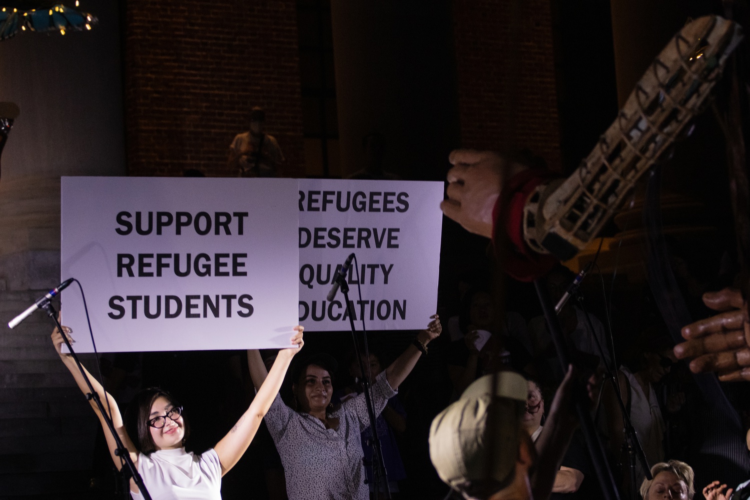 Volunteers in Harvard Yard held signs advocating for refugee rights during Amal's visit.