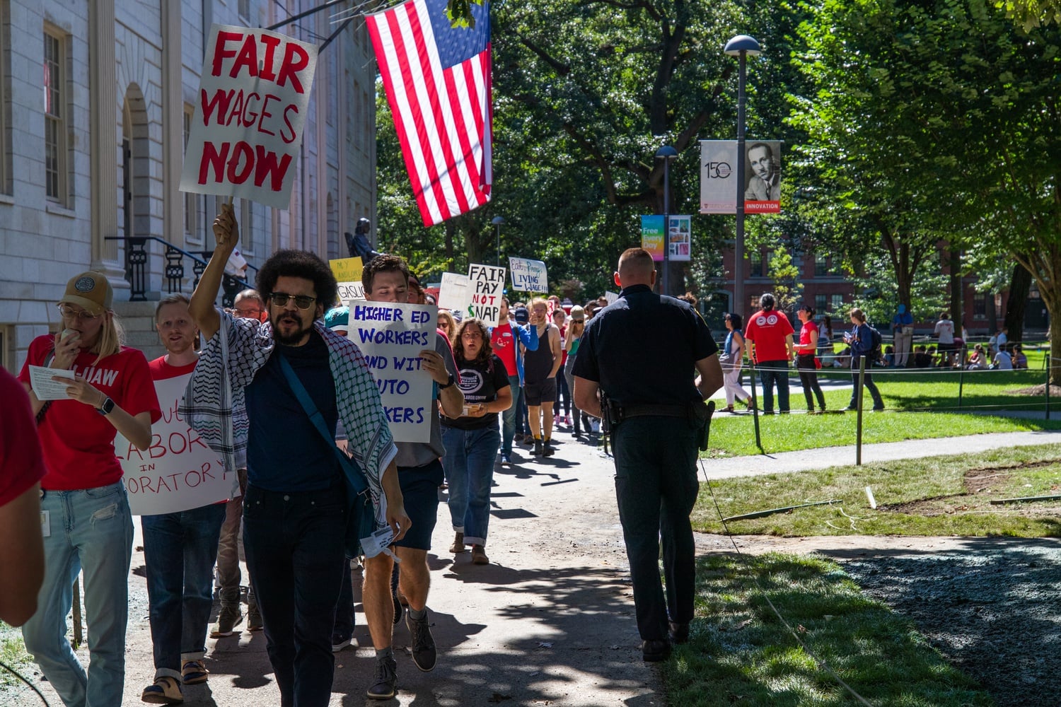 Harvard affiliates march in front of University Hall to demand higher wages Thursday afternoon.