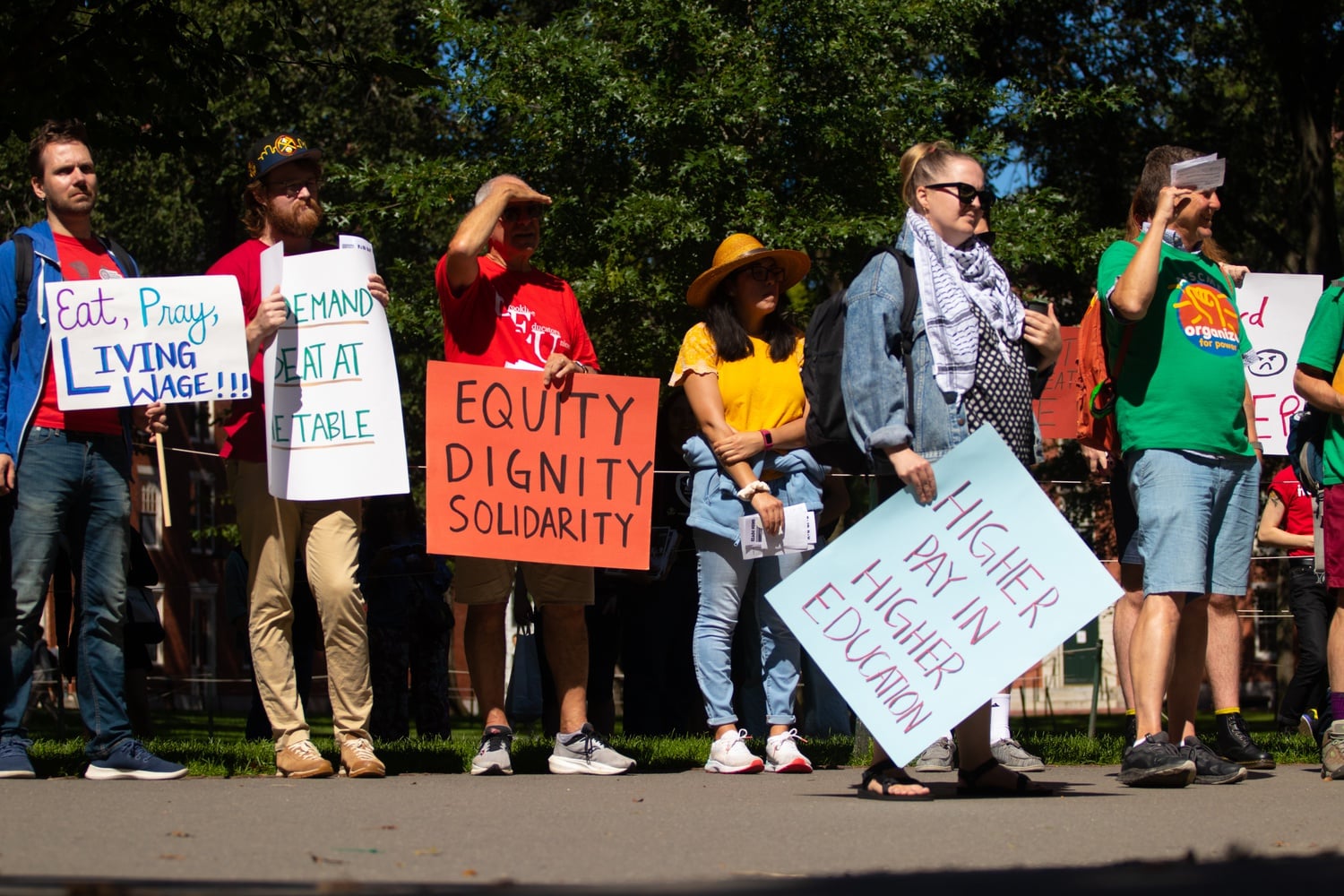 HGSU protestors hold signs and listen to speeches at the John Harvard statue Thursday afternoon.