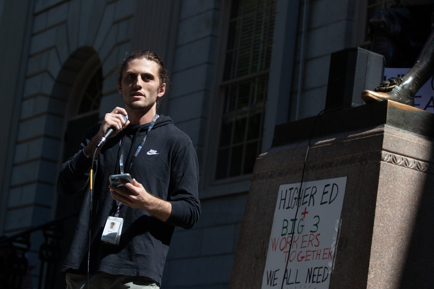 Broad Institute employee Michael Glass addresses protestors at the John Harvard statue on Thursday afternoon.