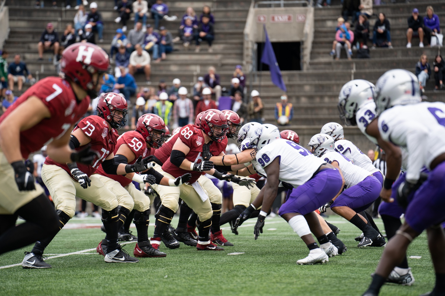 The Harvard football offensive players settle up against St. Thomas' defensive linemen at the Crimson's season opener last Saturday in Harvard Stadium. The Crimson took down the Tommies 45-13.
