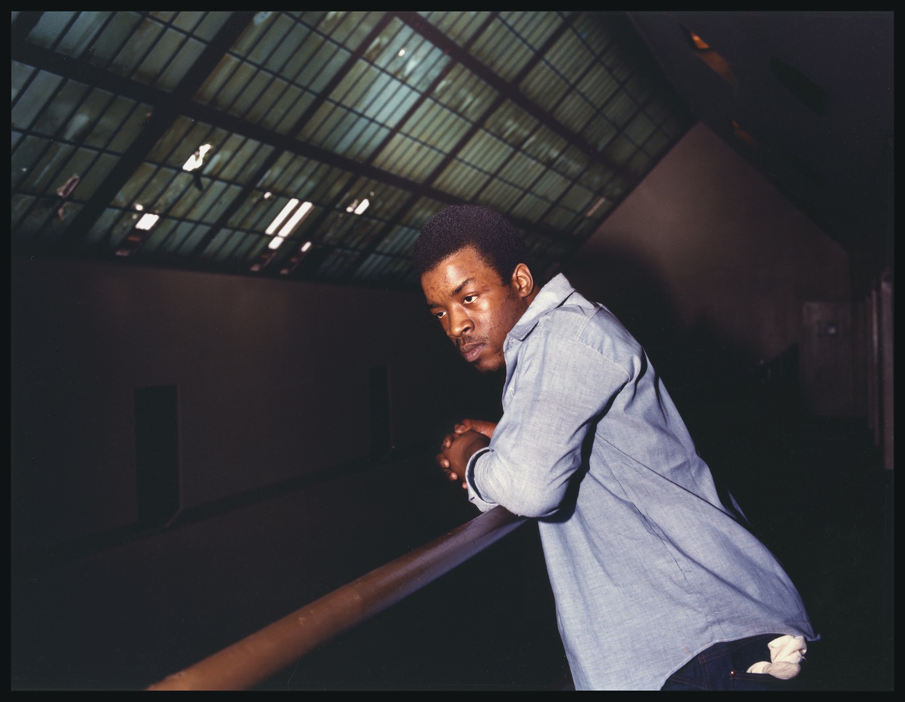 A man incarcerated at Walpole leans over a railing in his cell block.