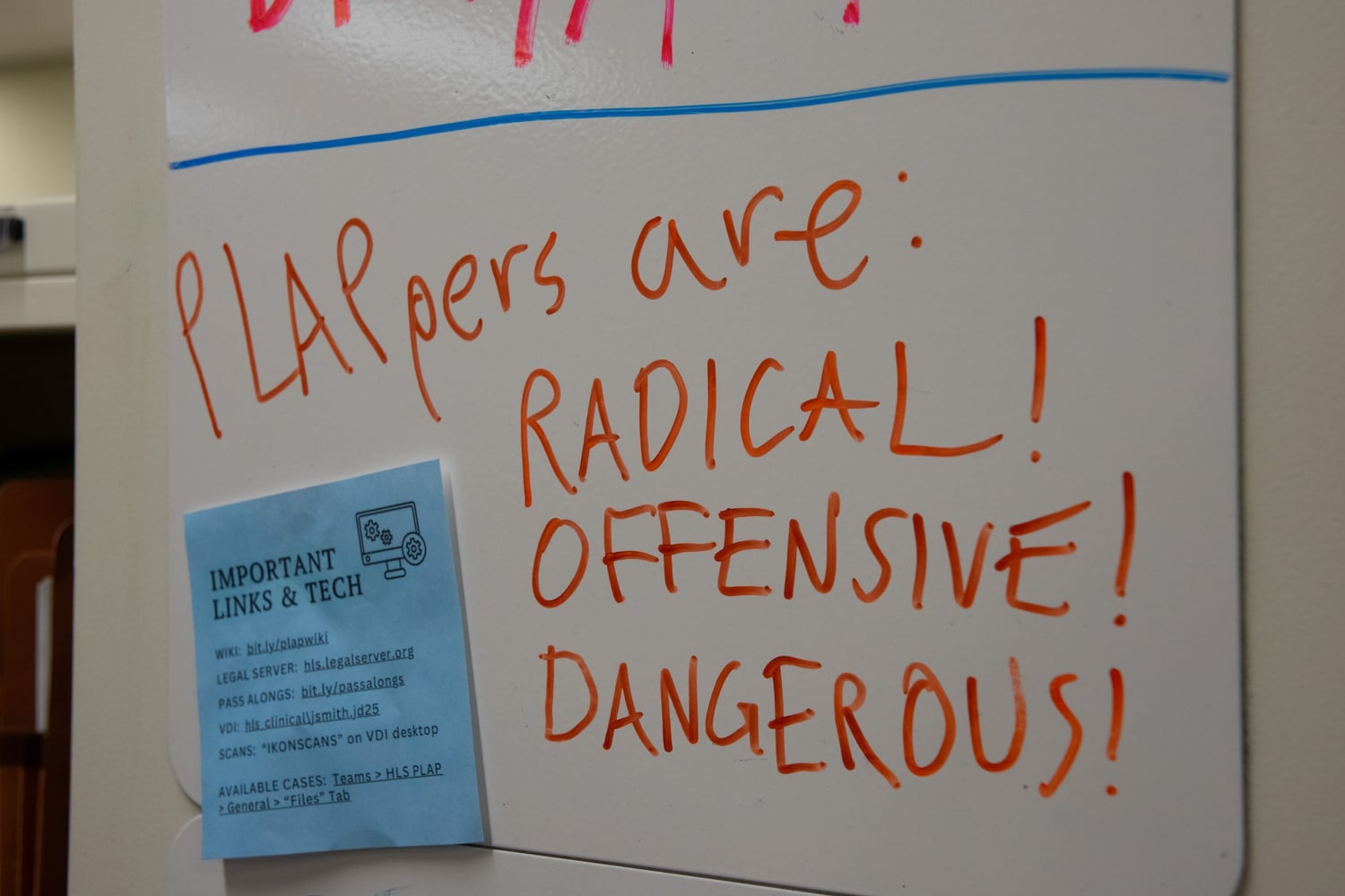 A whiteboard in the PLAP office at the Harvard Law School reads: PLAPpers are: RADICAL! OFFENSIVE! DANGEROUS!