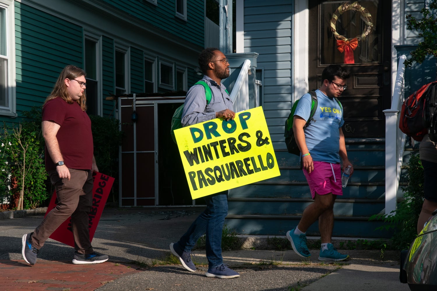A protester carries a sign reading "Drop Winters and Pasquarello," as he marches toward the house where the CCC's event was held.