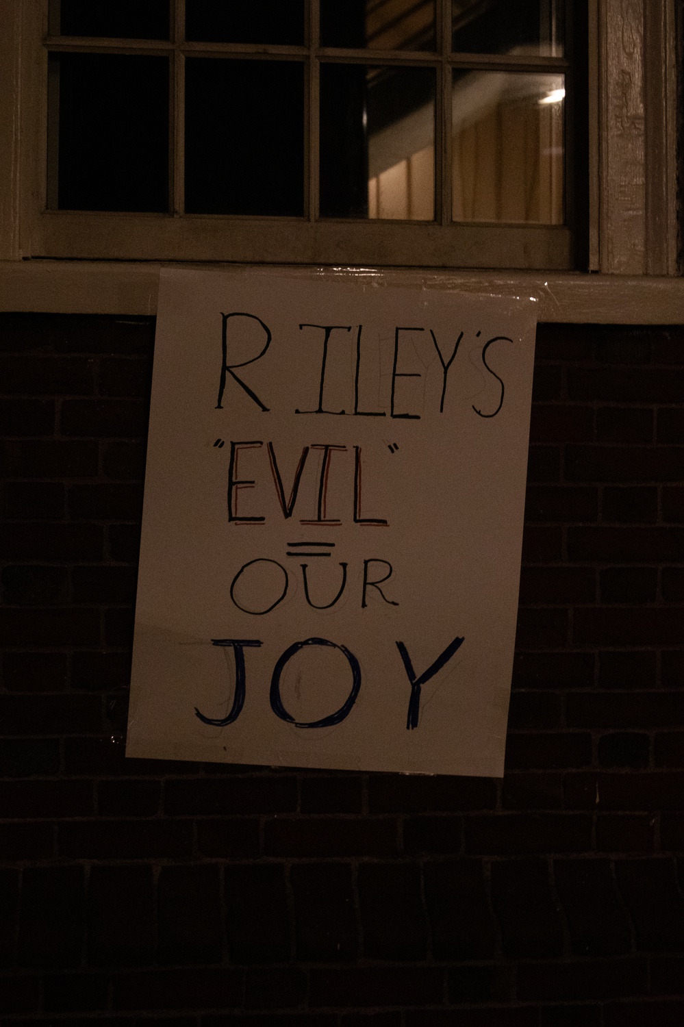 A sign that reads "Riley's Evil = Our Joy" hangs outside an event in Boylston Hall during which swimmer Riley Gaines spoke out against the participation of transgender people in sports.
