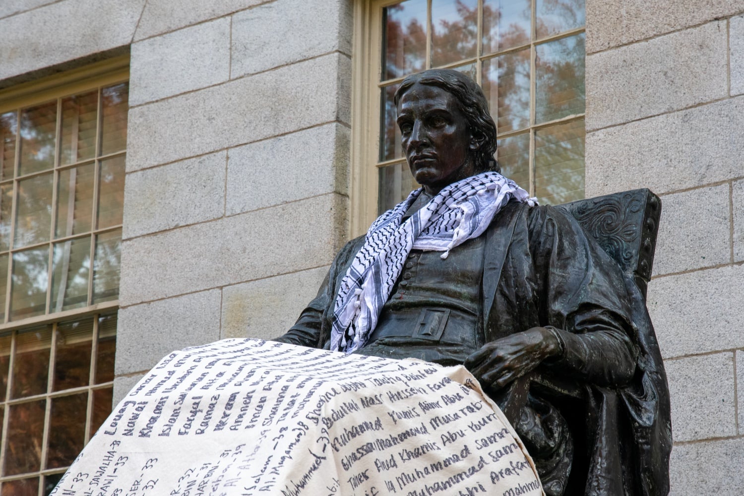 During the sit-in, supporters of the protest draped a canvas listing the names of Palestinians killed in Gaza over the John Harvard statue and placed a keffiyeh around its neck.