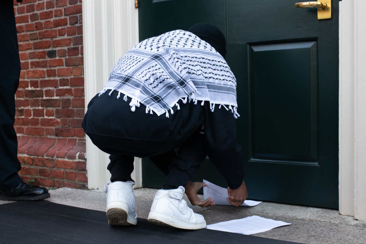 AFRO co-founder Kojo Acheampong '26 slides a copy of the demands under the door to Massachusetts Hall, which houses University President Claudine Gay's office.