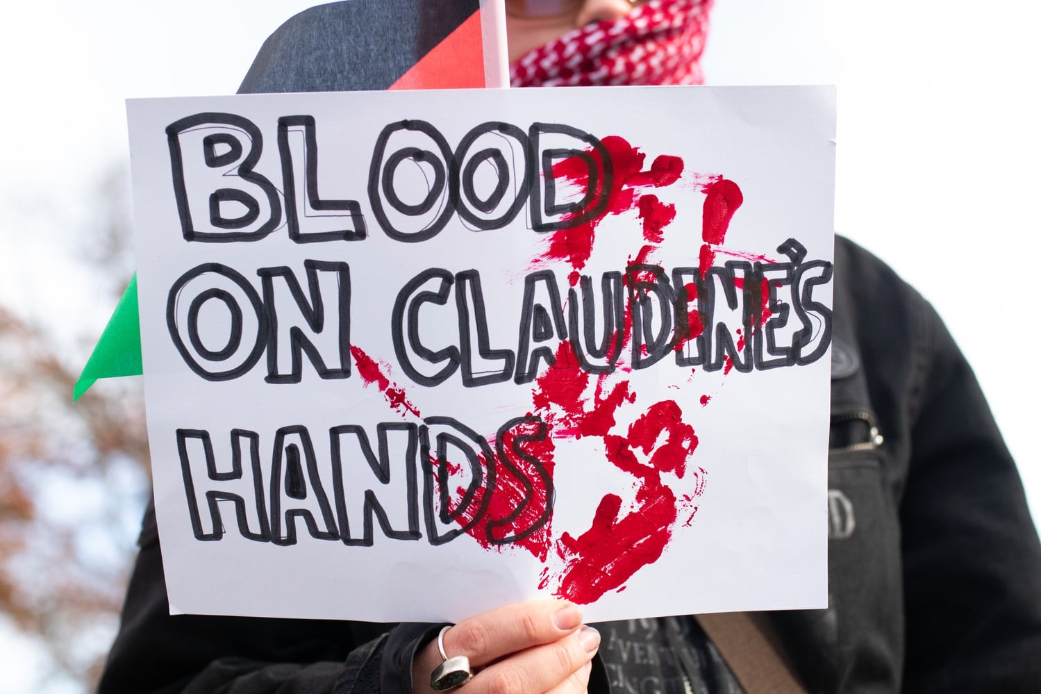 A pro-Palestine protester holds a sign reading "Blood on Claudine's Hands" — referencing Harvard's president, Claudine Gay — at a Wednesday demonstration in the Science Center Plaza following a walkout.